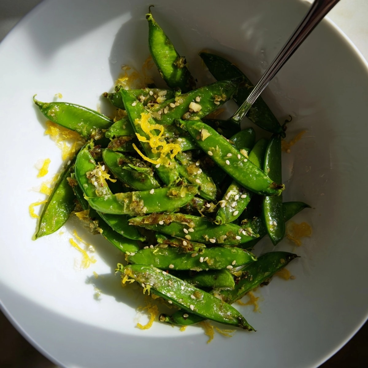 Crisp-tender sugar snap peas recipe glistening with olive oil, garlic aroma fills the air.