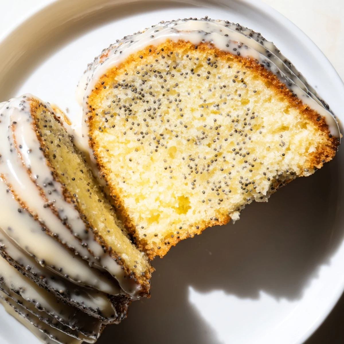 Close-up of a perfectly frosted Lemon Poppy Seed Bundt Cake, showcasing the fluffy texture and poppy seeds. 