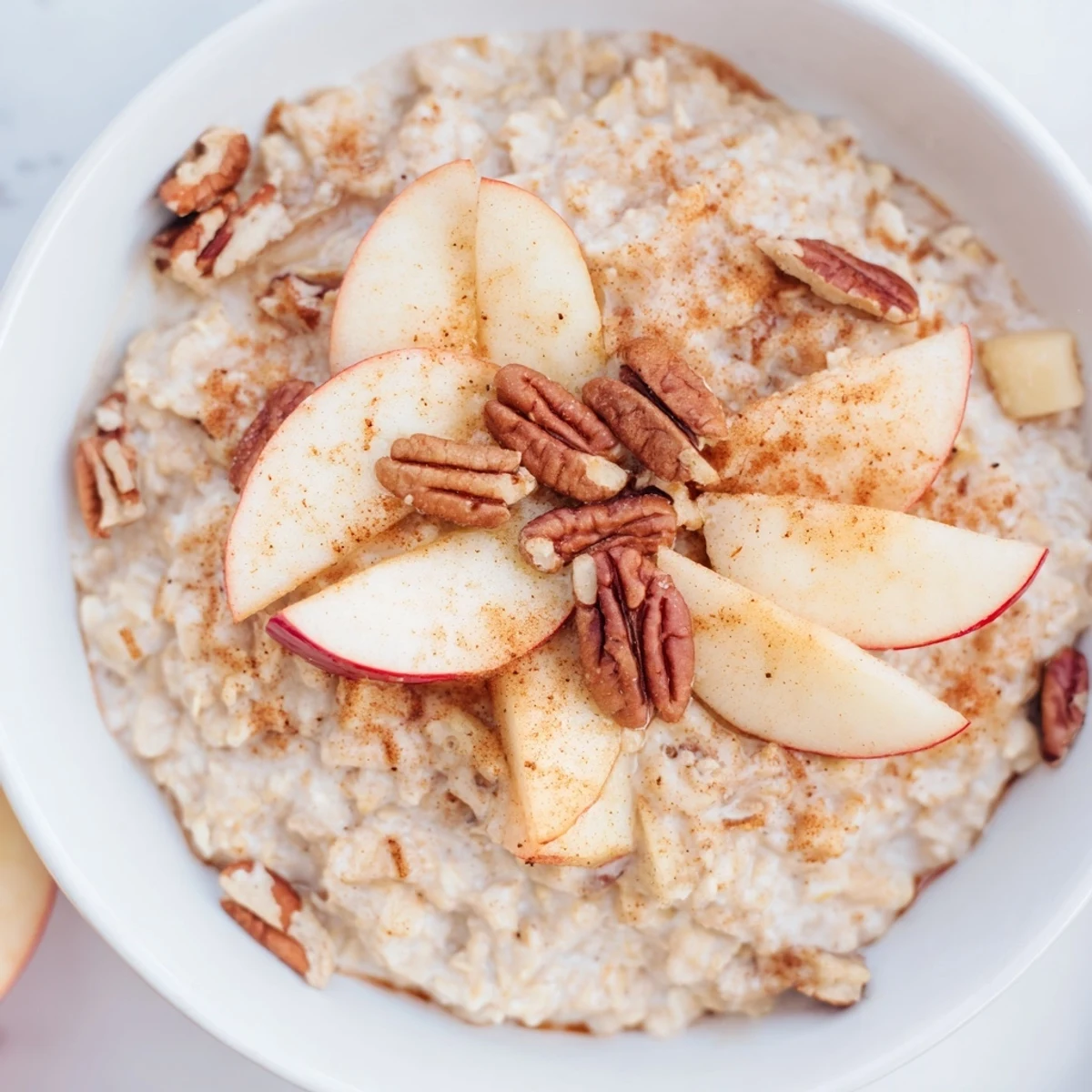 A close-up of creamy, delicious warm apple cinnamon oatmeal with golden apples and cinnamon spice.
