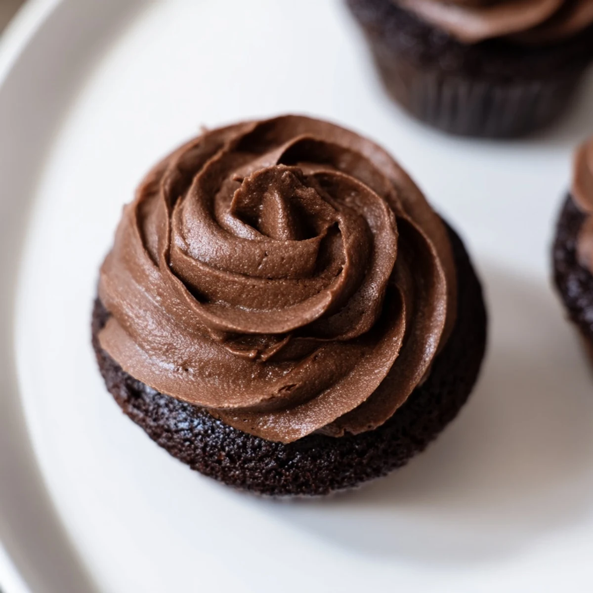 Swirls of rich, chocolate cupcake frosting tempt the eye, ready to be spread over freshly baked treats.