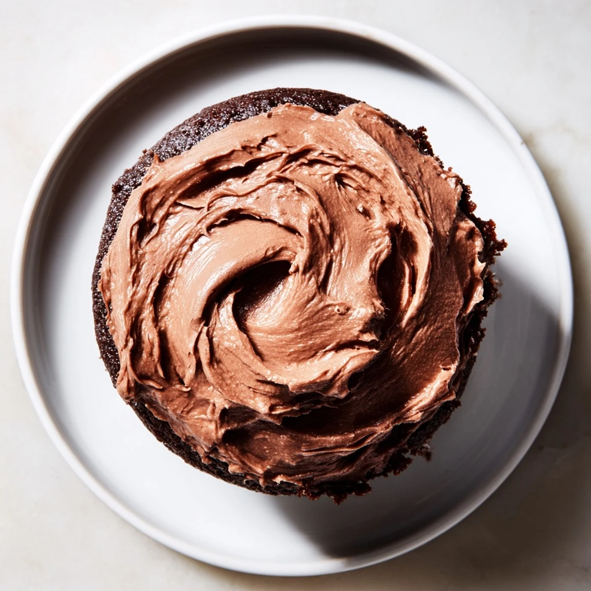 A decadent close-up showcases smooth, dark chocolate cupcake frosting, perfect for any occasion.