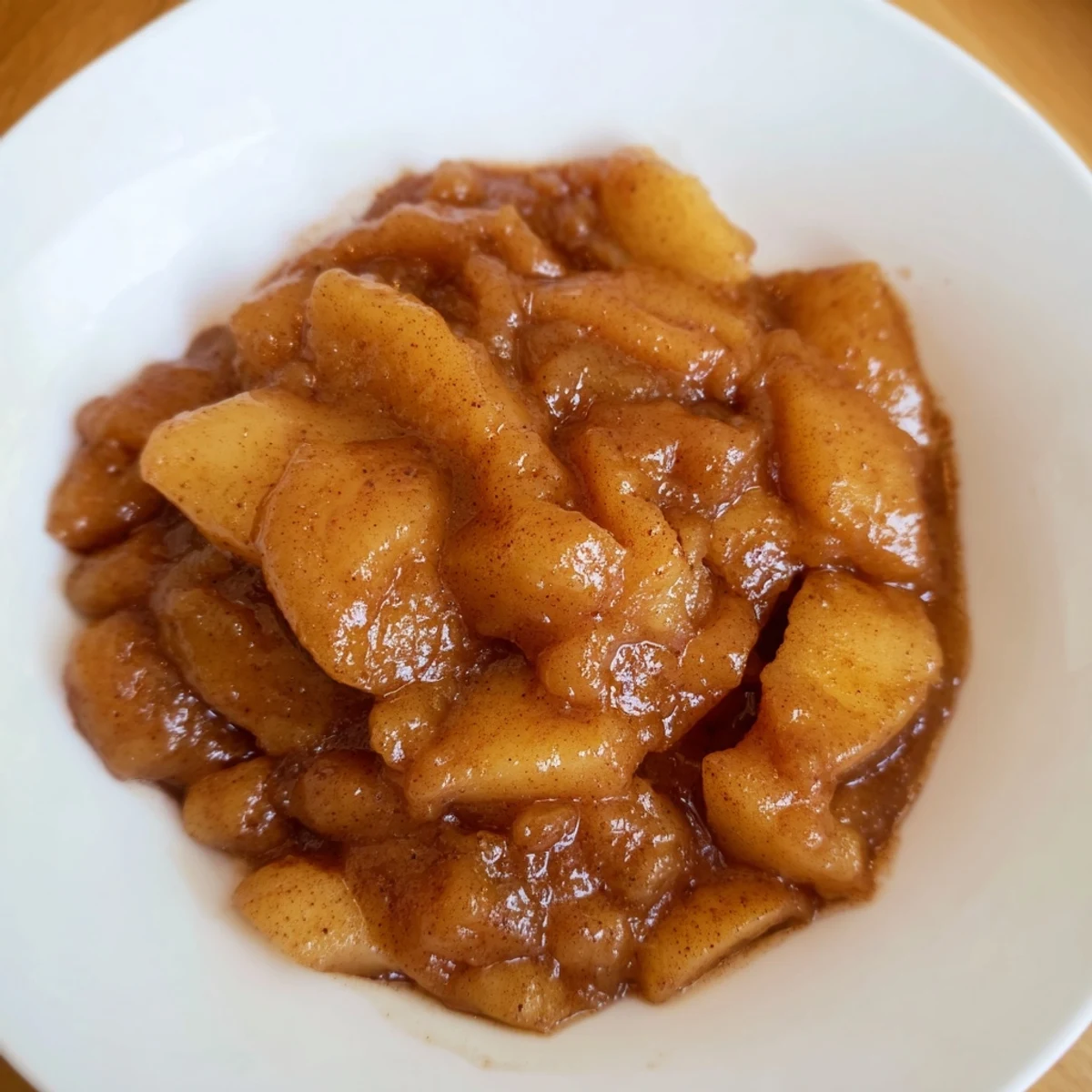A vibrant, chunky bowl of spiced apple sauce, perfect as a topping for pancakes or oatmeal.
