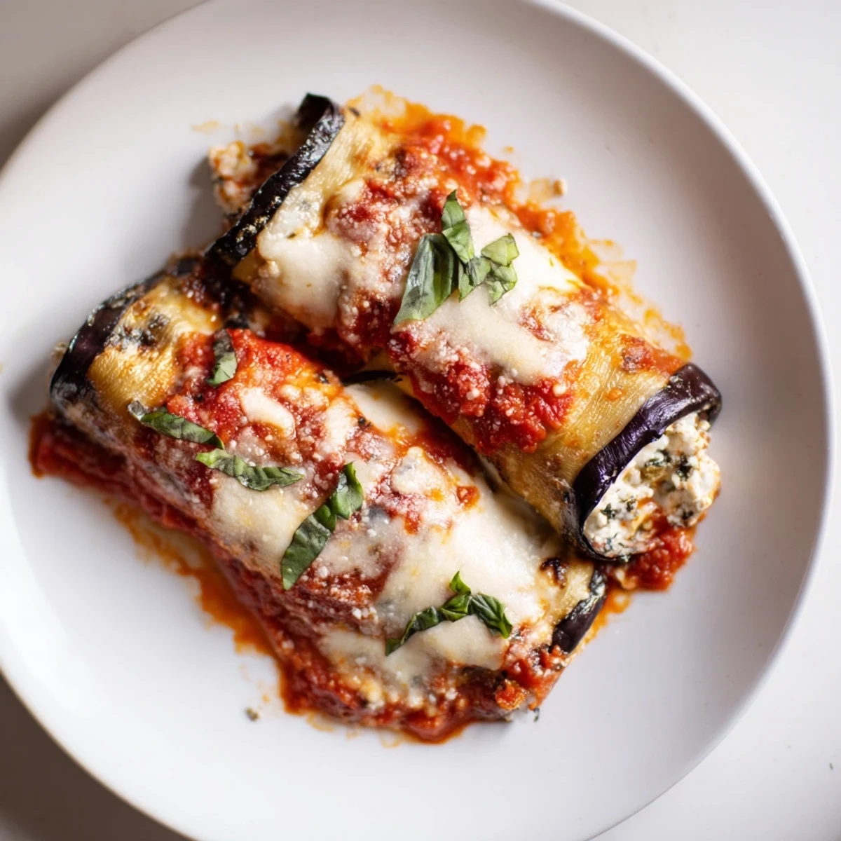 Golden, baked Baked Eggplant Rollatini with cheesy topping and fresh basil garnish, a delicious meal.