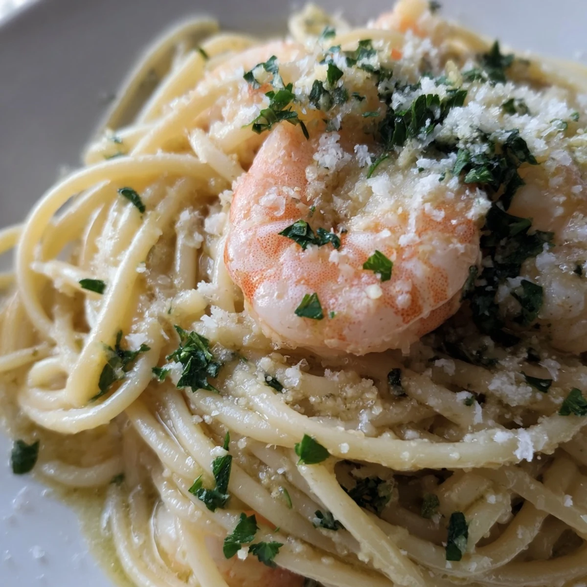 Plated Lemon Shrimp Pasta is served with a glass of white wine, fresh lemon wedges, and Parmesan cheese.