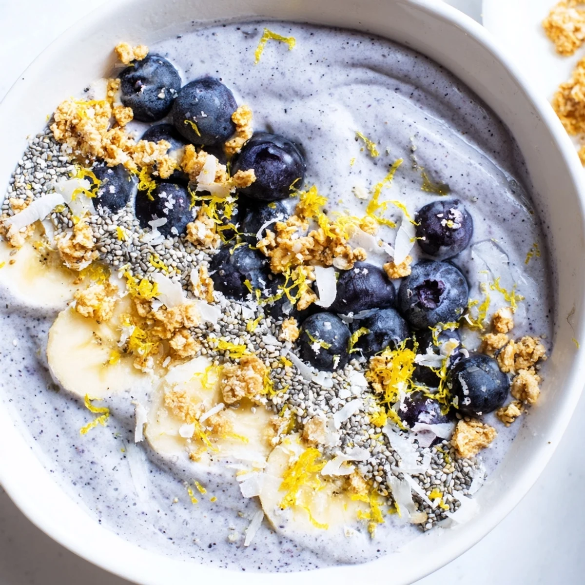 Thick, creamy Lemon Blueberry Smoothie Bowl topped with fresh berries, granola, and chia seeds.