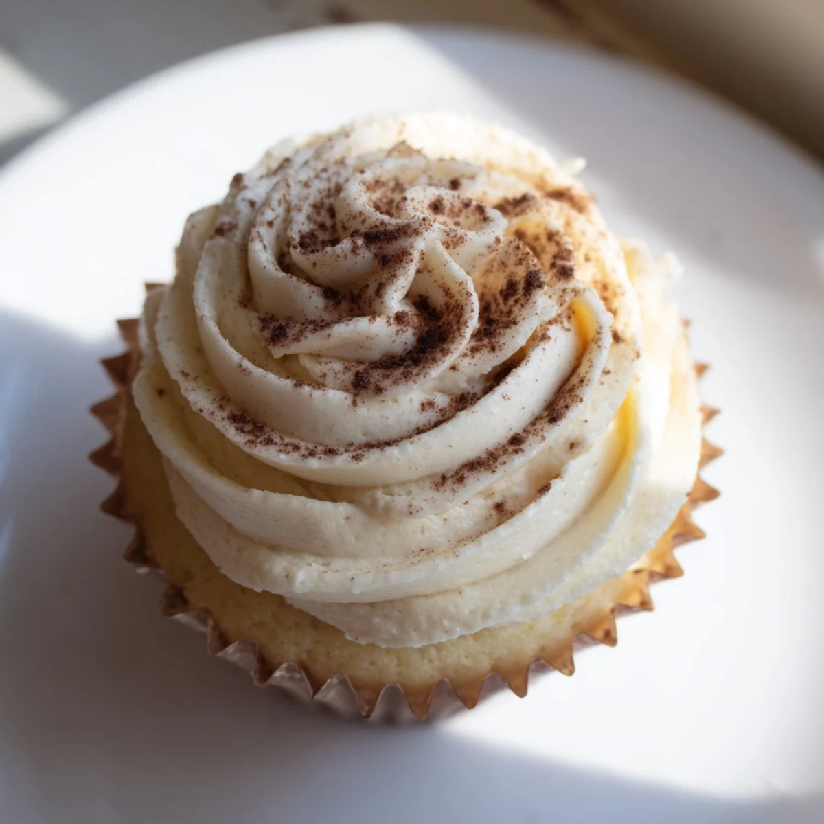 On a white plate, Irish Cream Cupcakes feature moist vanilla cake and rich frosting, perfect for St. Patrick's Day or celebrations.