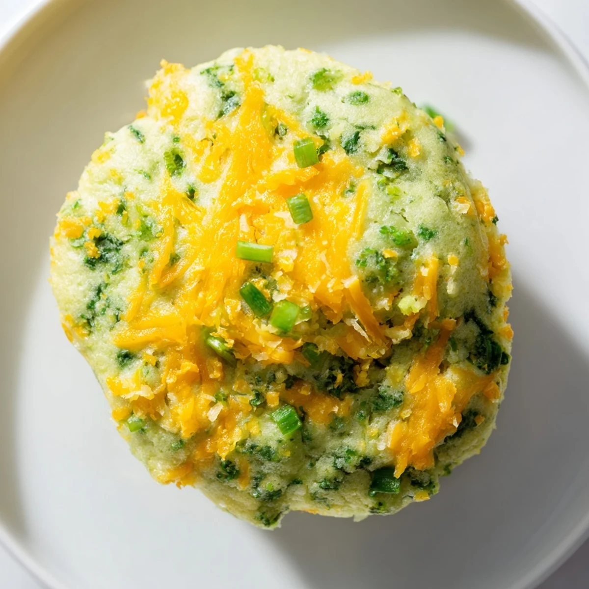 Freshly baked St. Patricks Day Spinach Muffins feature melted cheddar cheese and sliced green onions on top.