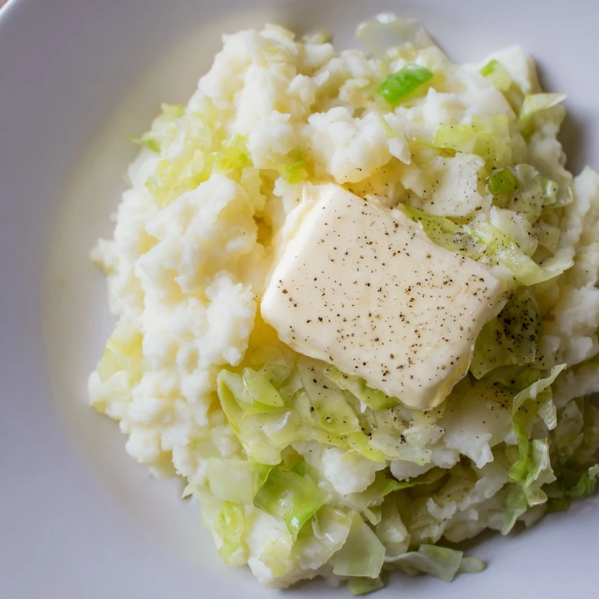 A rustic bowl of Irish Cabbage and Potato Mash with tender green cabbage folded into fluffy potatoes and buttery milk.