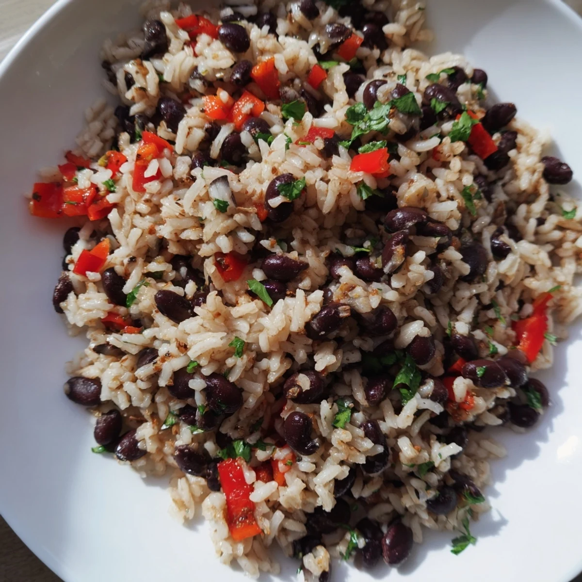 Hearty rice and beans with spices garnished with fresh cilantro, served warm in a rustic ceramic bowl.  