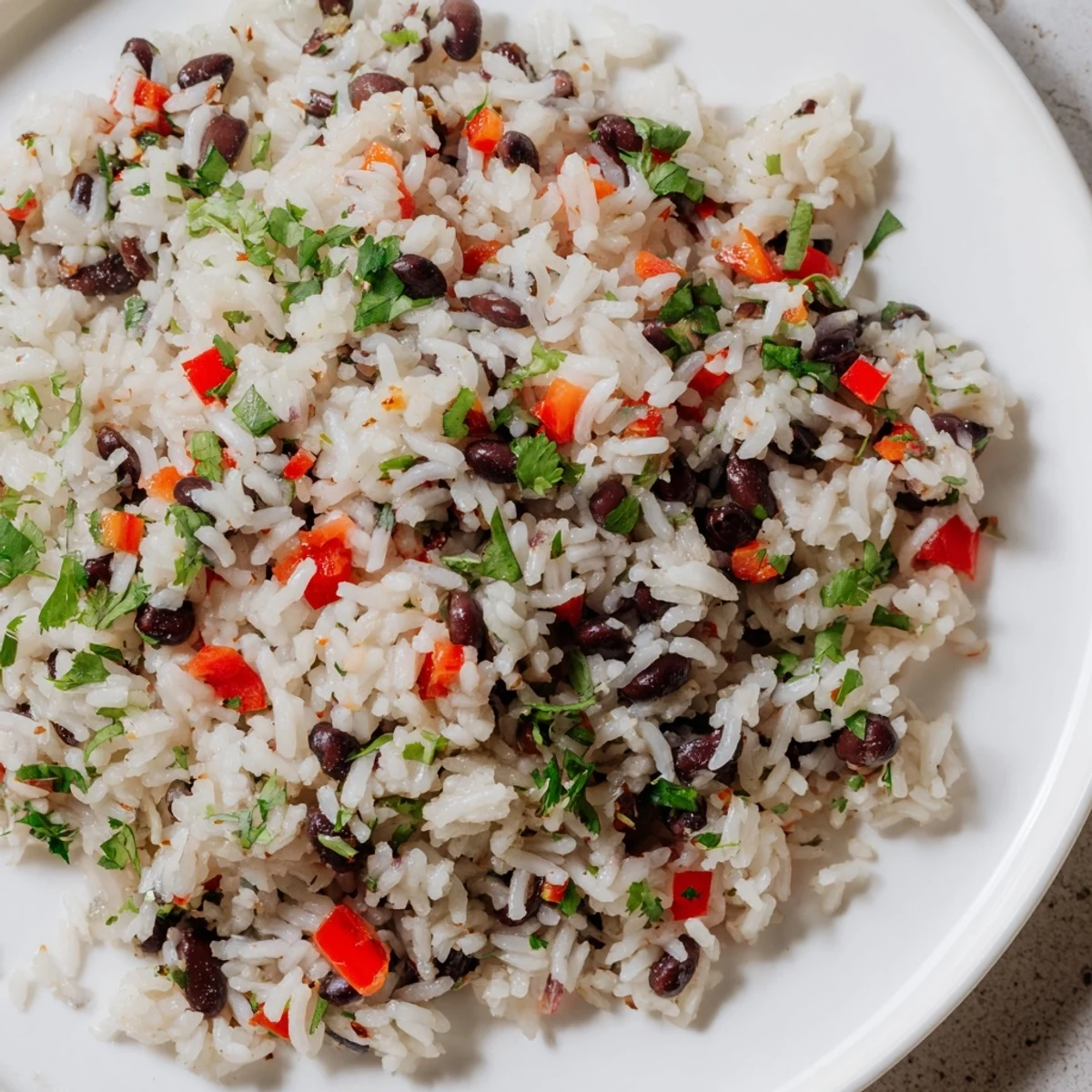 Fluffy white rice and tender black beans simmered with cumin and smoked paprika, garnished with fresh cilantro and lime wedges in a rustic bowl.