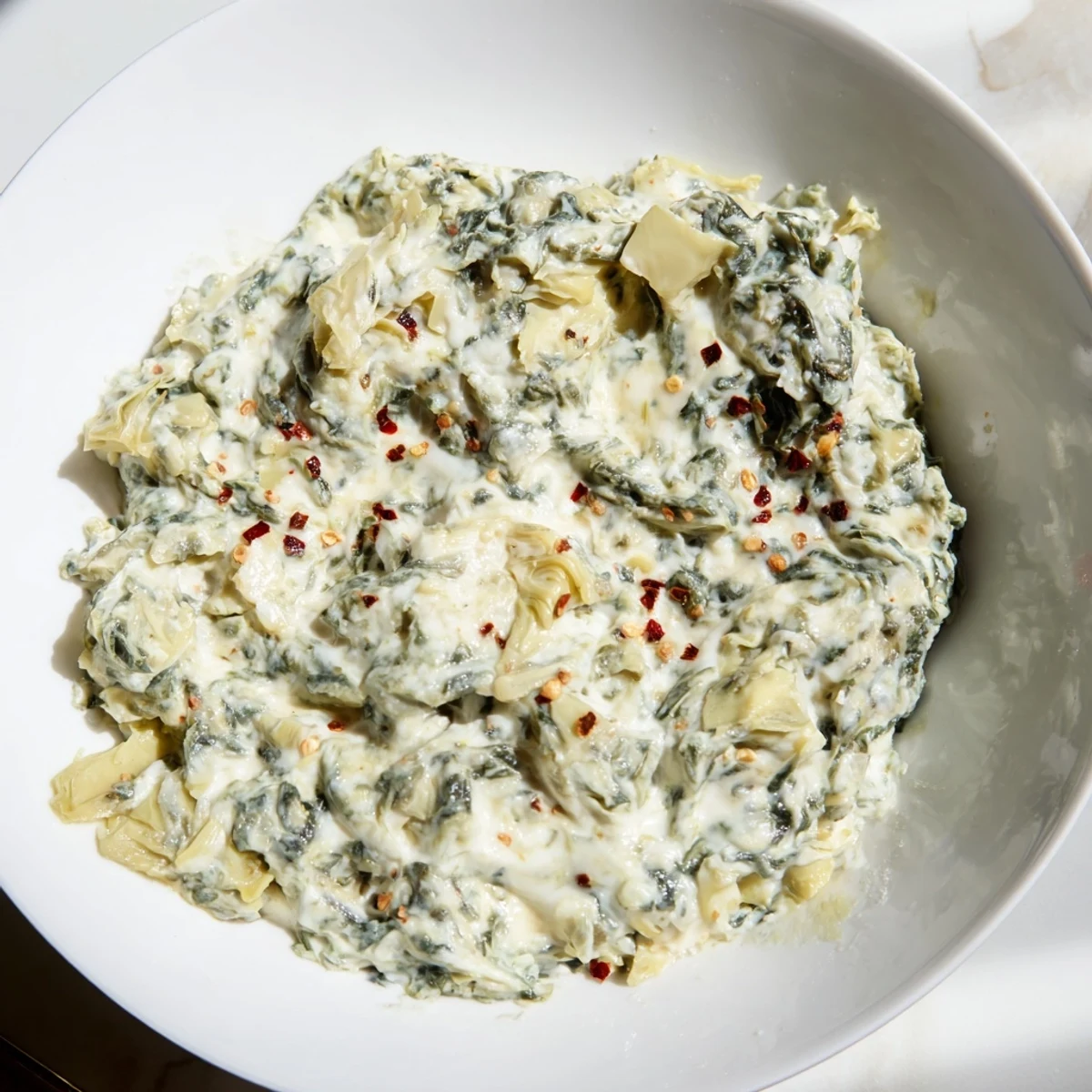 Freshly baked Spinach Dip with Artichokes and Cheese, featuring a creamy texture and golden, cheesy crust on top.