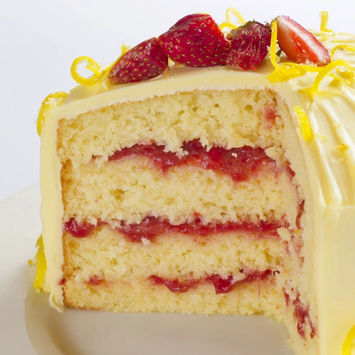 Freshly frosted Strawberry Lemonade Layer Cake with Buttercream, lemon zest and sliced strawberries on top.