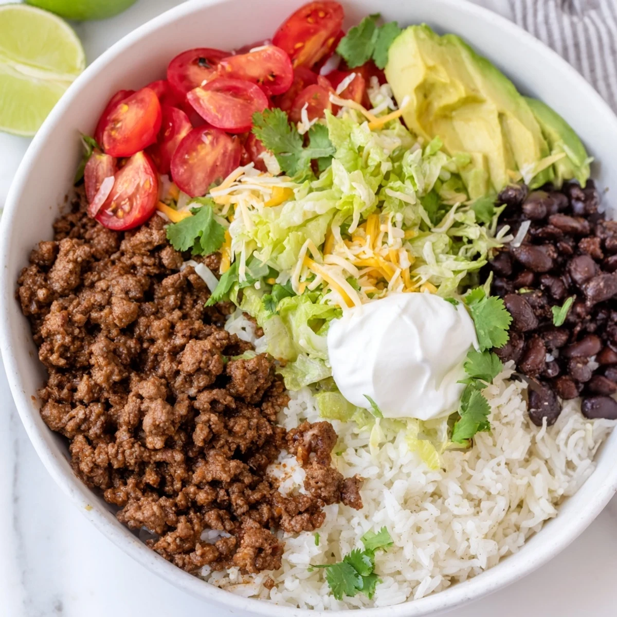A close-up of the Beef Burrito Bowls with Rice and Beans shows seasoned beef, black beans, and melted cheese over fluffy cilantro rice.