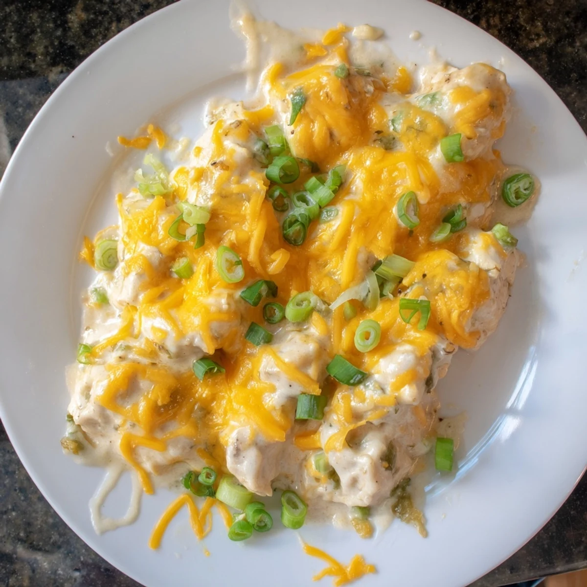 Hearty Sour Cream and Onion Chicken fresh from the oven, bubbling with savory sauce and garnished with fresh green onion slices.