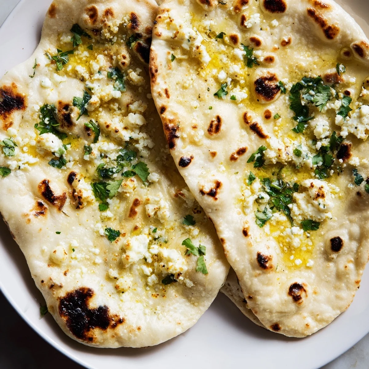 Homemade Cottage Cheese Garlic Naan stacked on a wooden board, garnished with cilantro, ready to be enjoyed with dal.