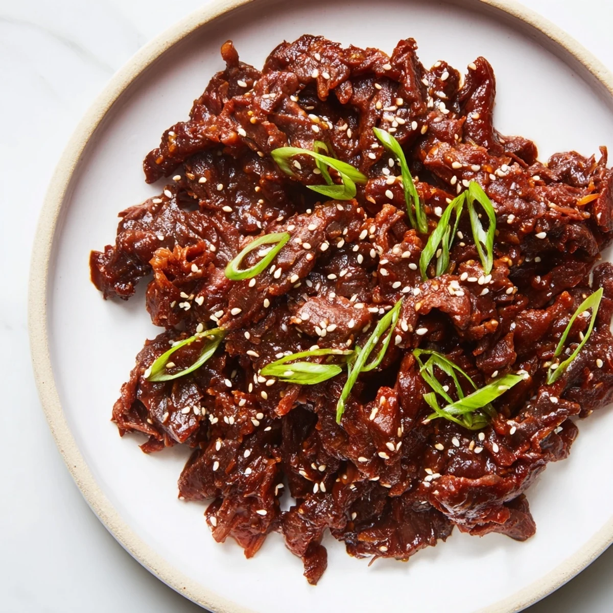 Tender Slow Cooker Korean Beef plated with steamed vegetables and drizzled with savory sweet sauce.