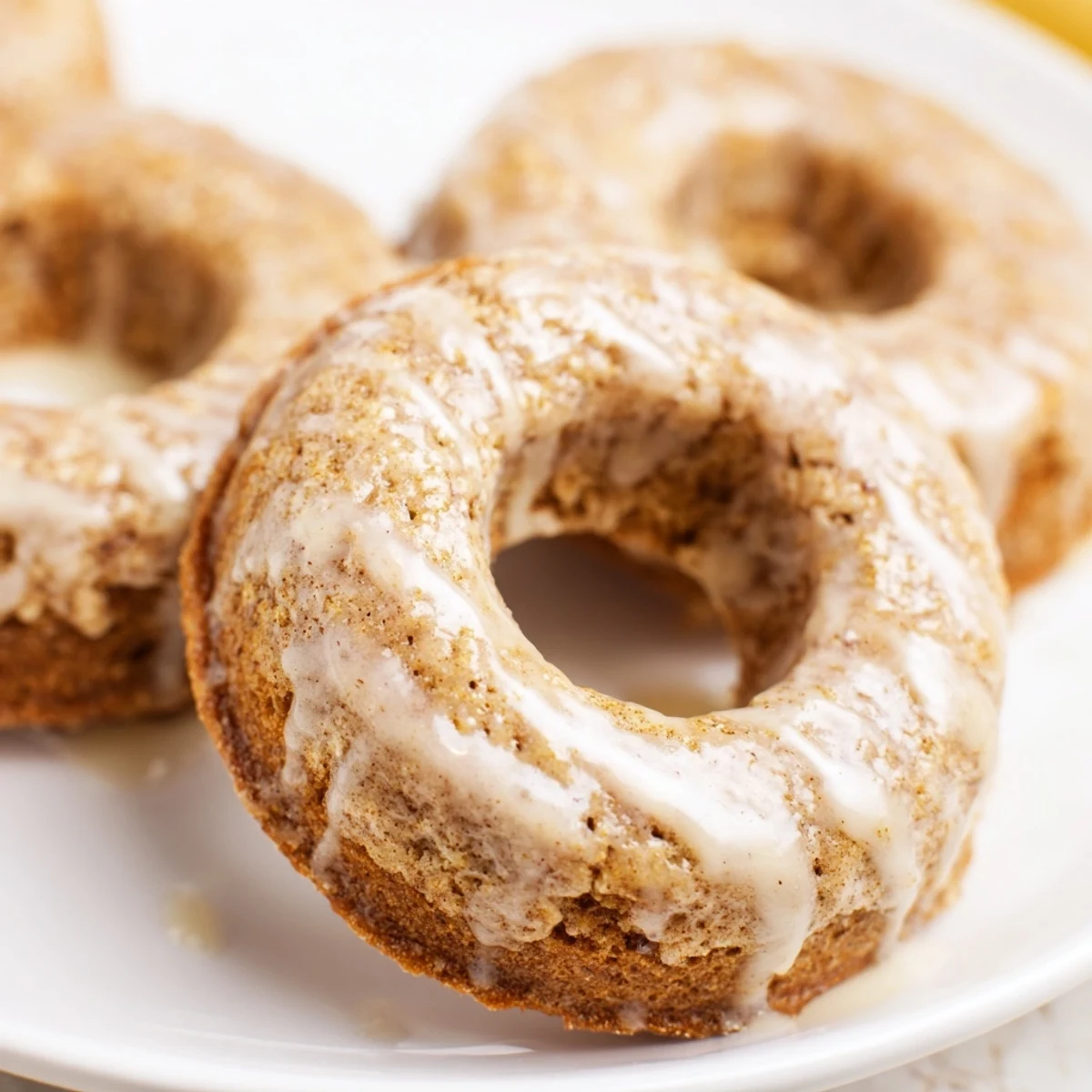 Glazed Baked Banana Bread Donuts rest on a wire rack with a sweet vanilla drizzle and ripe banana aroma.
