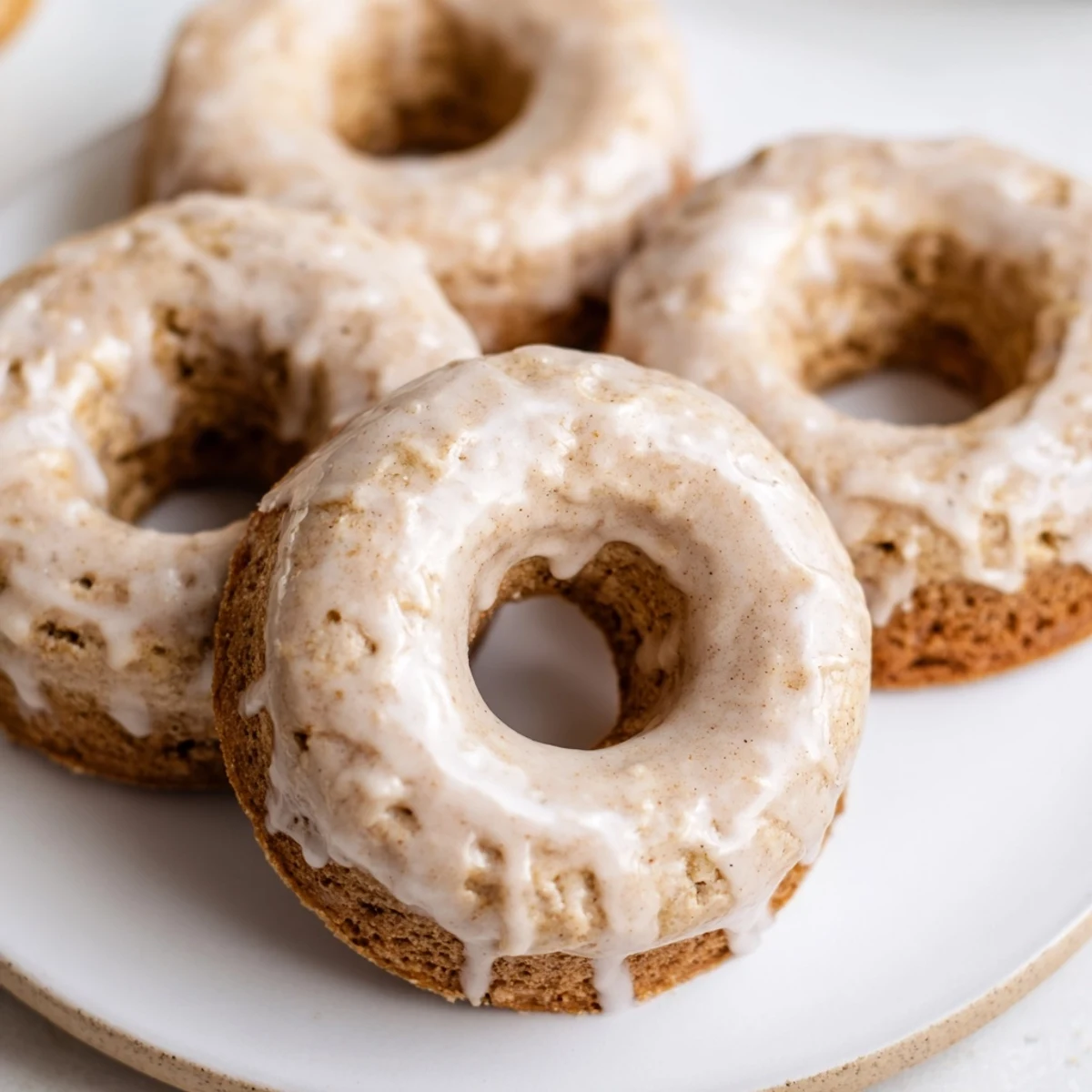 Twelve moist Baked Banana Bread Donuts are arranged on a platter, perfect for a snack or cozy morning treat.
