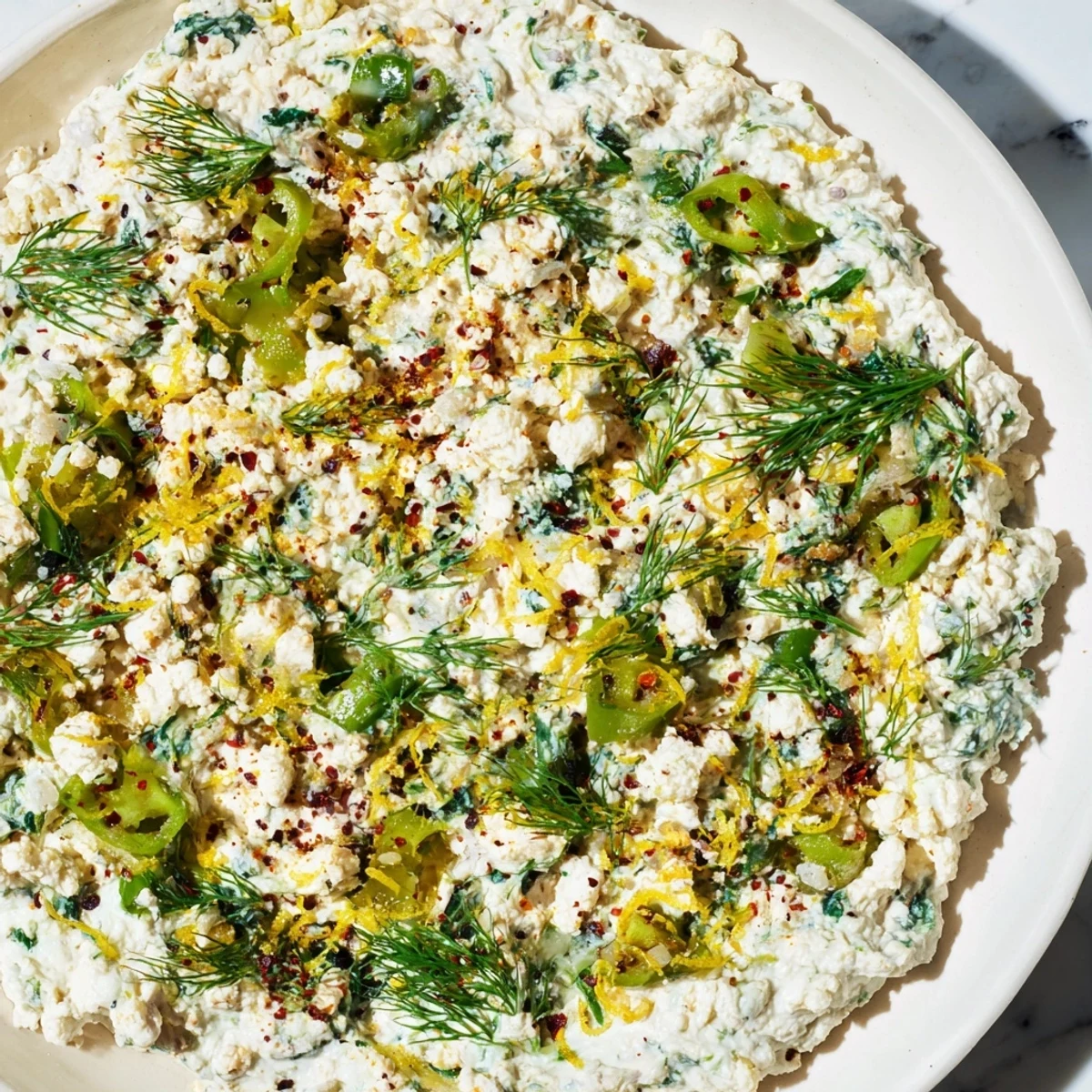 Fresh Spinach and Pepperoncini Baked Feta Dip topped with herbs, served warm with crunchy pita chips for dipping on a wooden board.