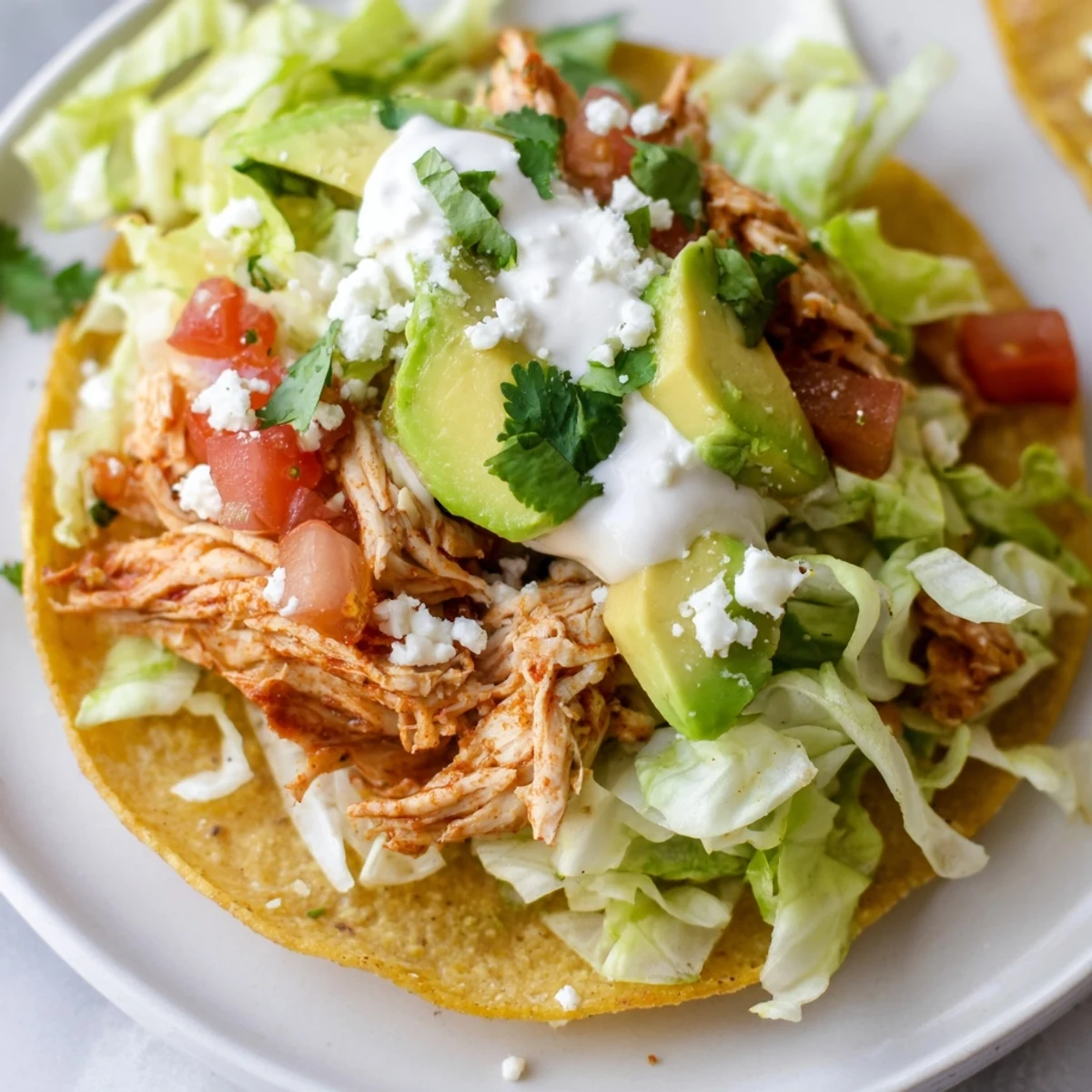 Golden, crispy mini chicken tostadas topped with creamy avocado and fresh pico de gallo on a rustic wooden board.