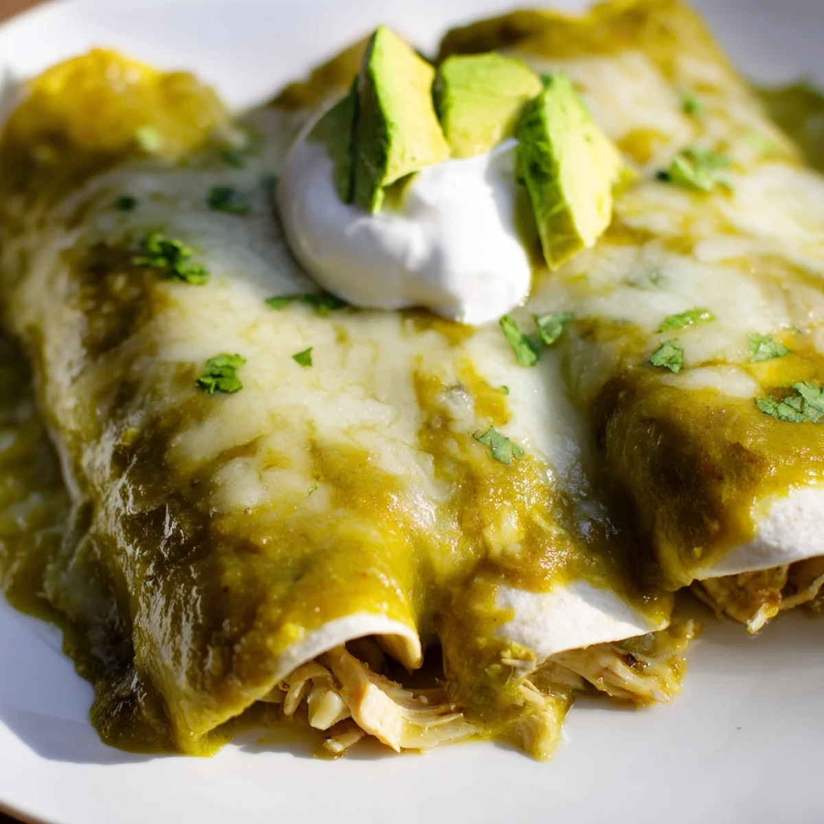 Fresh cilantro garnishes a serving of Green Enchiladas With Chicken topped with avocado.