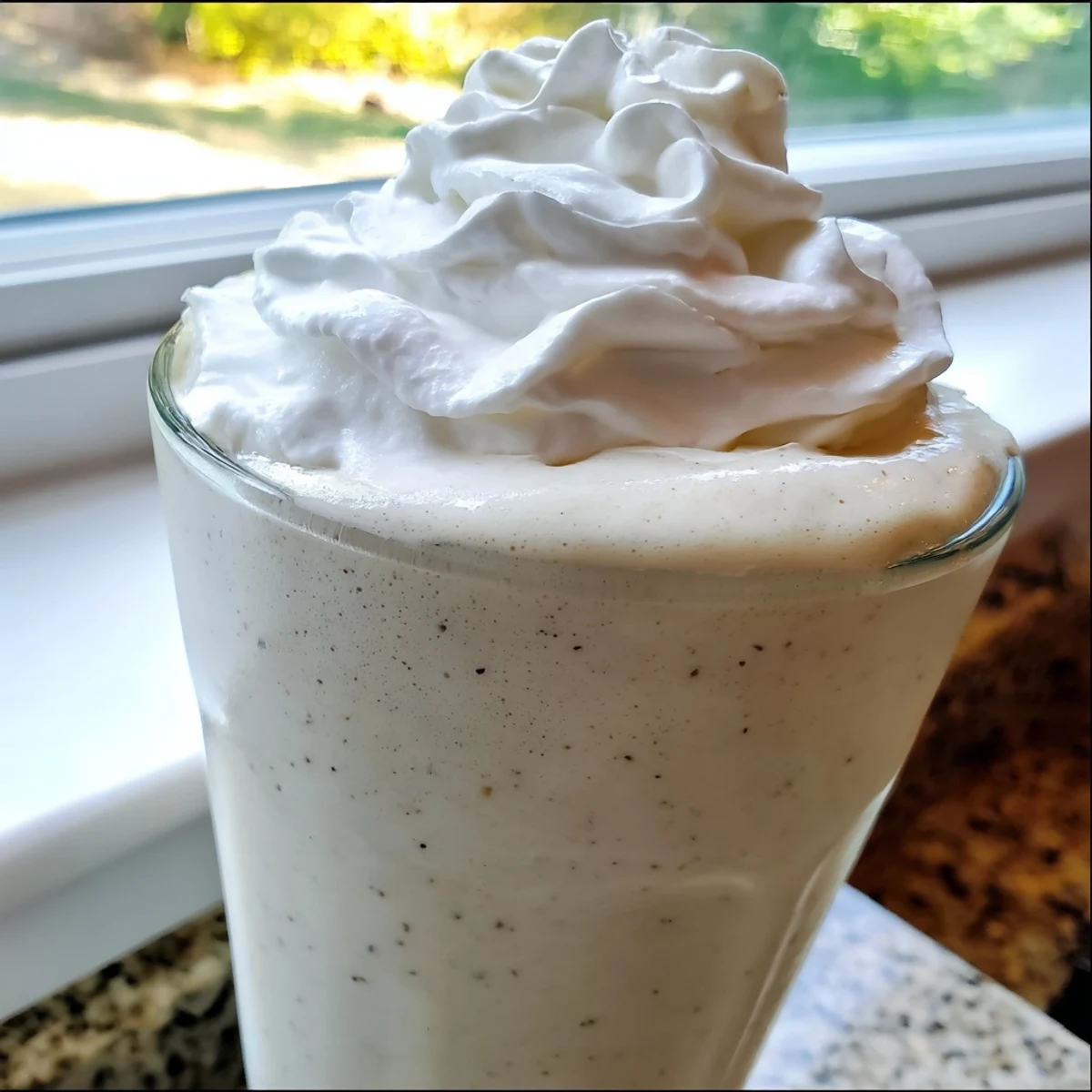 Creamy Starbucks Vanilla Bean Frappuccino topped with whipped cream in a tall glass.