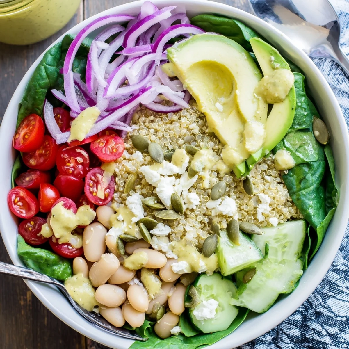This Spinach & White Bean Ultimate Protein Power Bowl features quinoa, cucumbers, and cherry tomatoes ready for a healthy lunch.