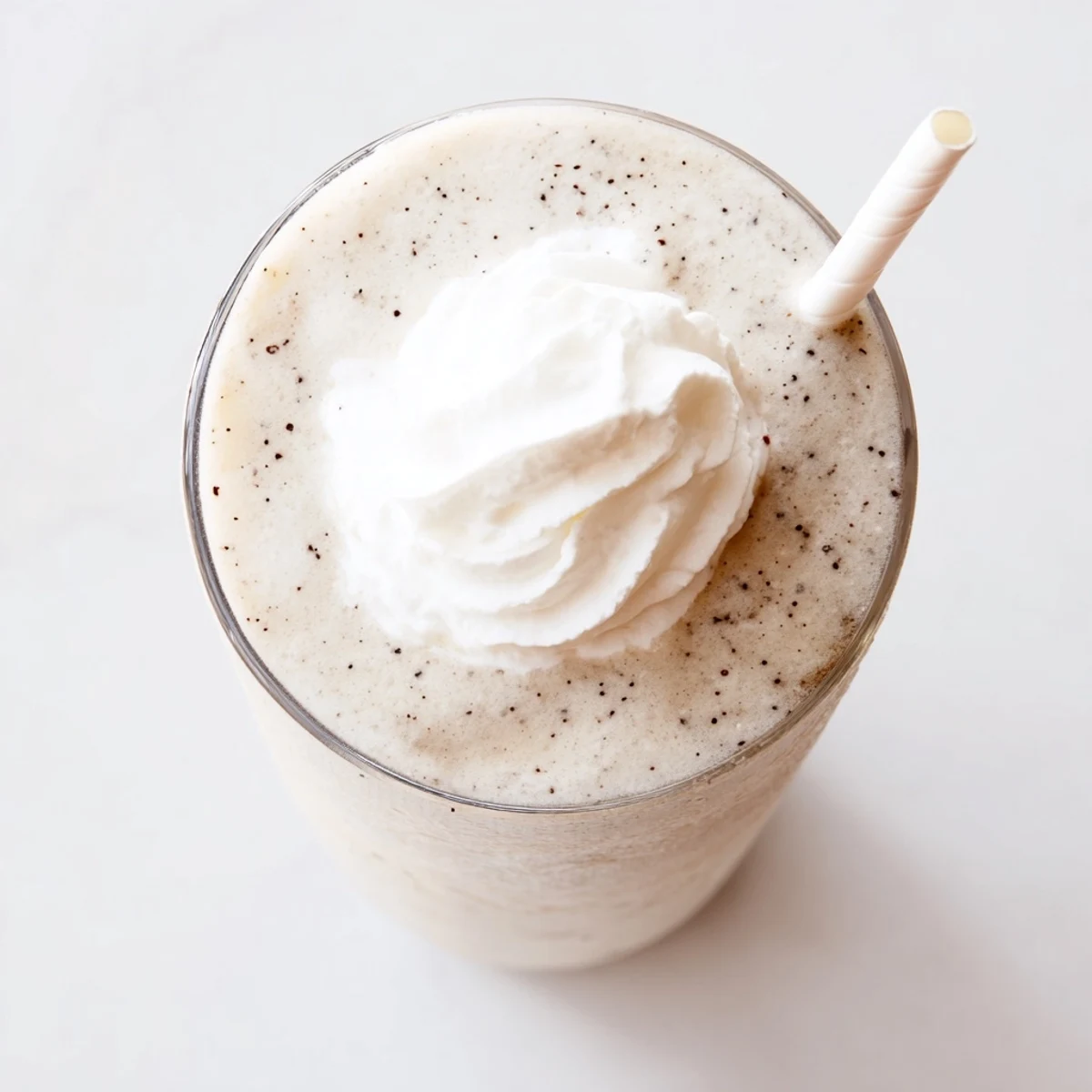 Homemade Vanilla Bean Frappuccino blended with ice and milk, served with a striped straw.