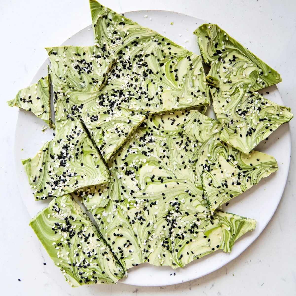 A close-up of cracked matcha and black sesame bark pieces arranged neatly for an elegant dessert platter.