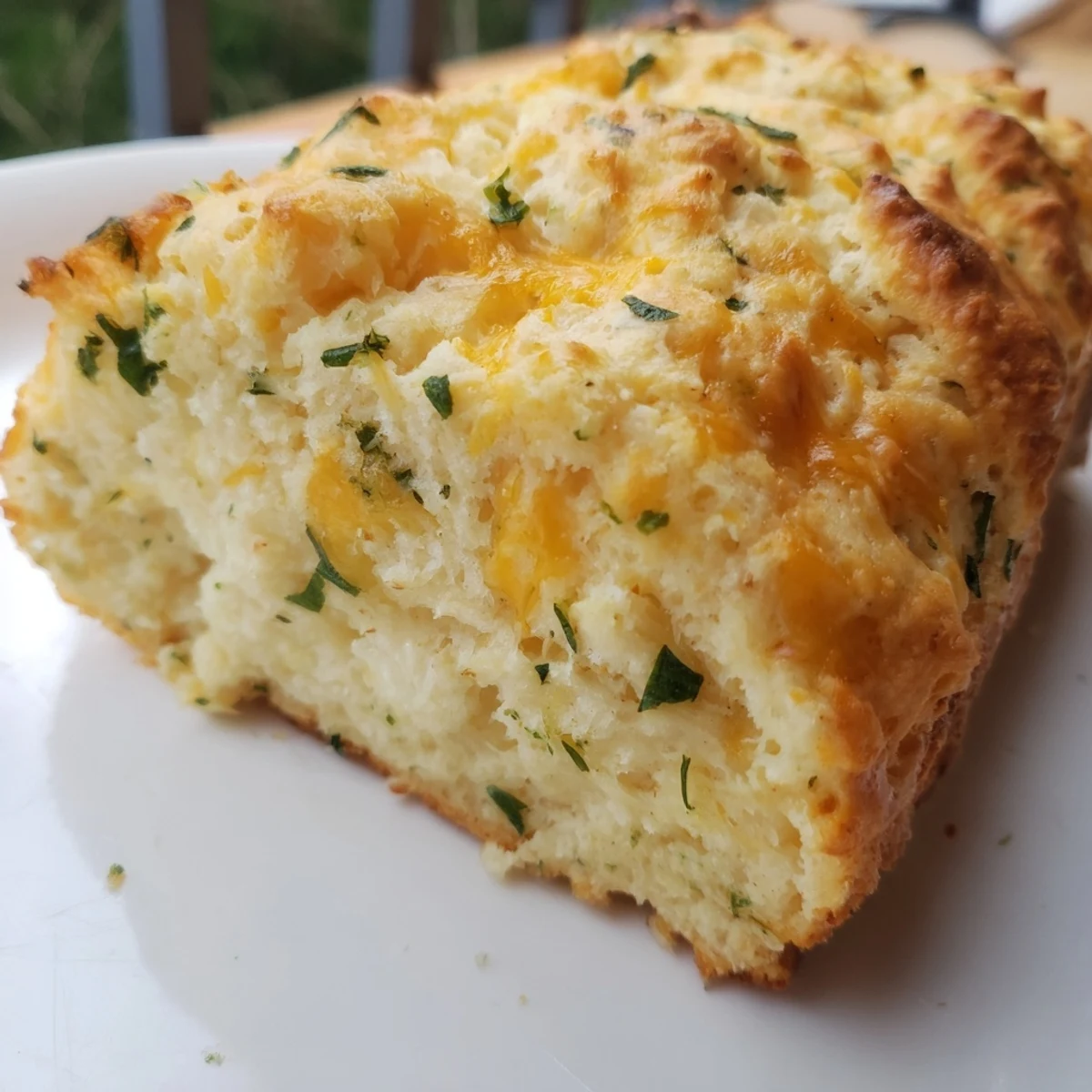 Golden-brown Red Lobsters Cheddar Bay Biscuit Loaf sliced open to reveal fluffy, cheesy layers and specks of green parsley.