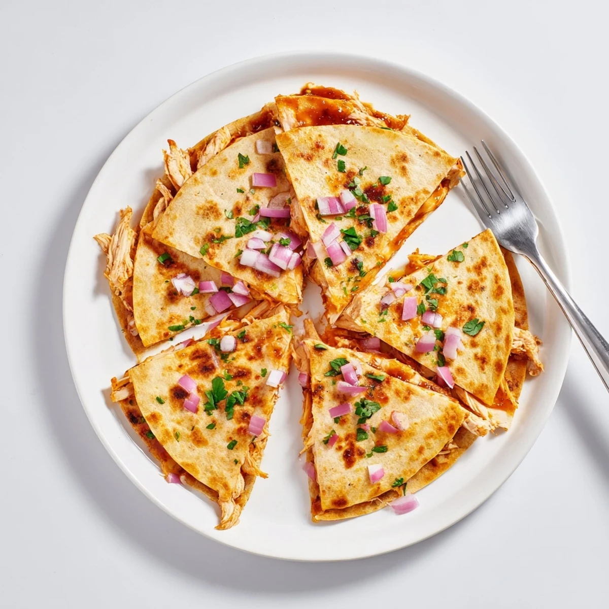 A close-up view shows the crispy tortilla wedges of Hot Honey BBQ Chicken Quesadillas served with a side of sour cream. 