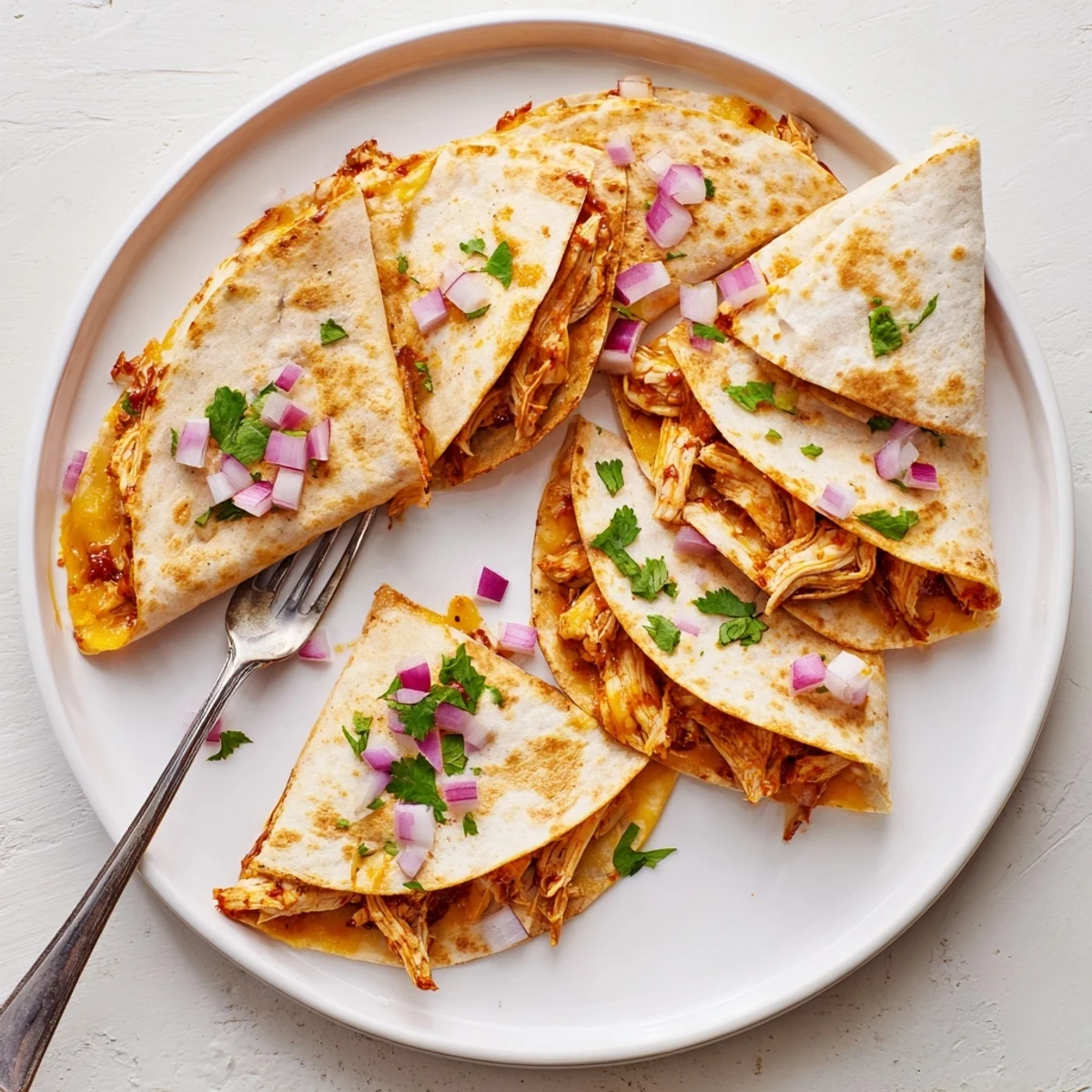 Fresh cilantro and diced red onion top the Hot Honey BBQ Chicken Quesadillas, highlighting the American-Mexican fusion flavors.