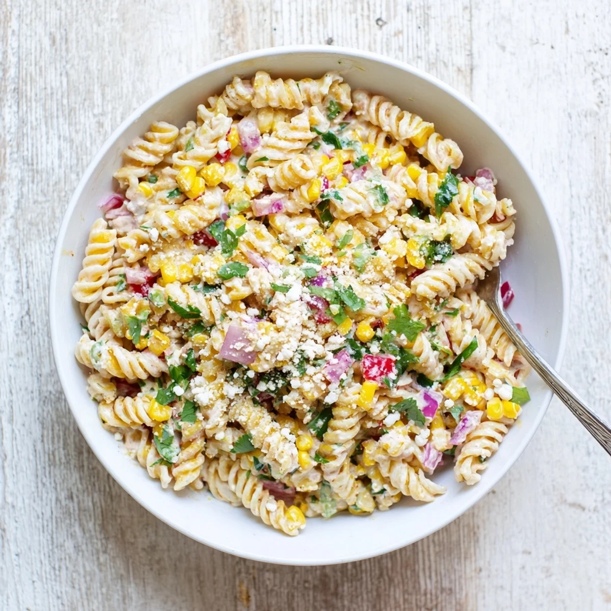 Creamy Mexican Street Corn Pasta Salad with charred corn, cotija cheese, and lime, served chilled in a rustic bowl.