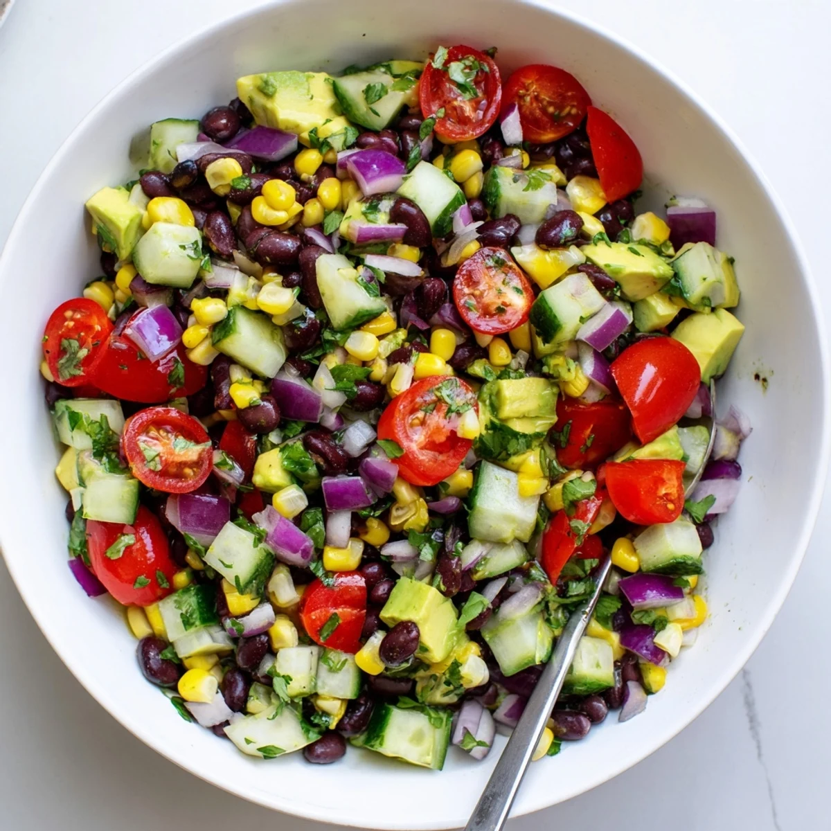 Colorful chopped black bean salad with fresh vegetables and creamy avocado in a serving bowl