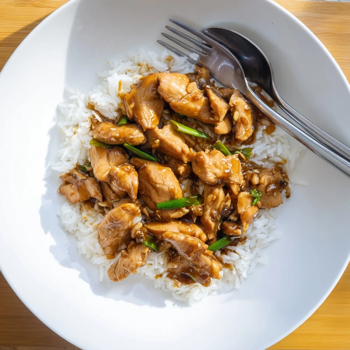 Golden brown Mongolian chicken pieces coated in glossy soy-ginger sauce atop steamed white rice