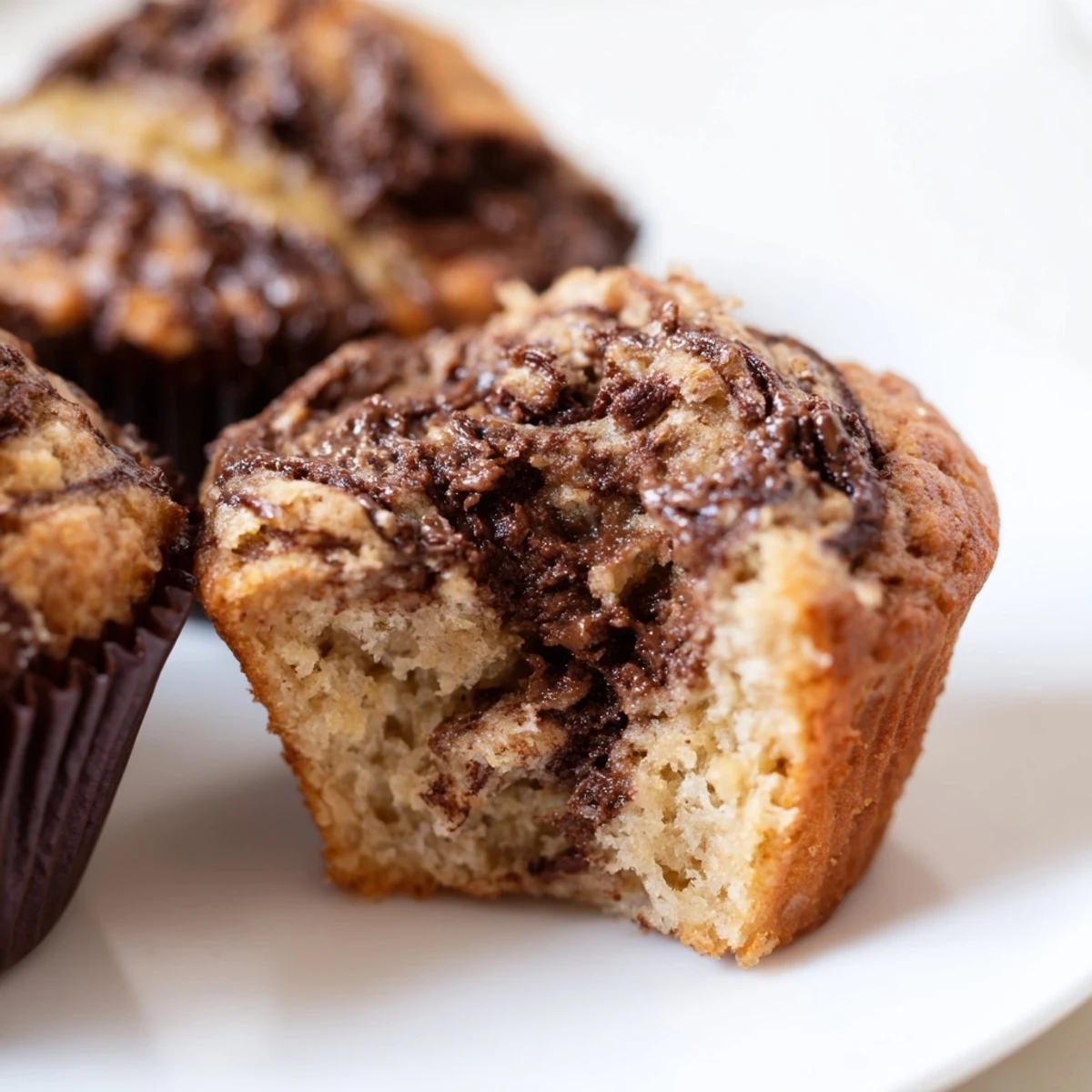 Soft banana muffins topped with a marbled Nutella swirl ready for breakfast or afternoon snacking