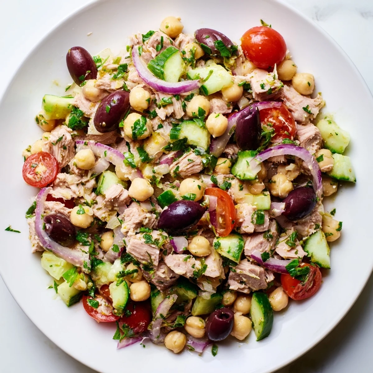 Colorful hearty tuna and garbanzo bean salad featuring fresh tomatoes, cucumber, and red onion in a bright lemon-herb dressing