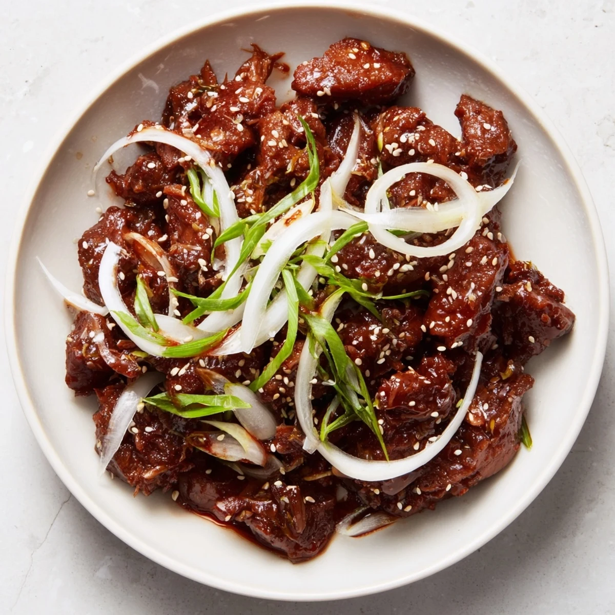 Shredded Slow Cooker Korean Beef in rich sweet-spicy sauce garnished with fresh green onions