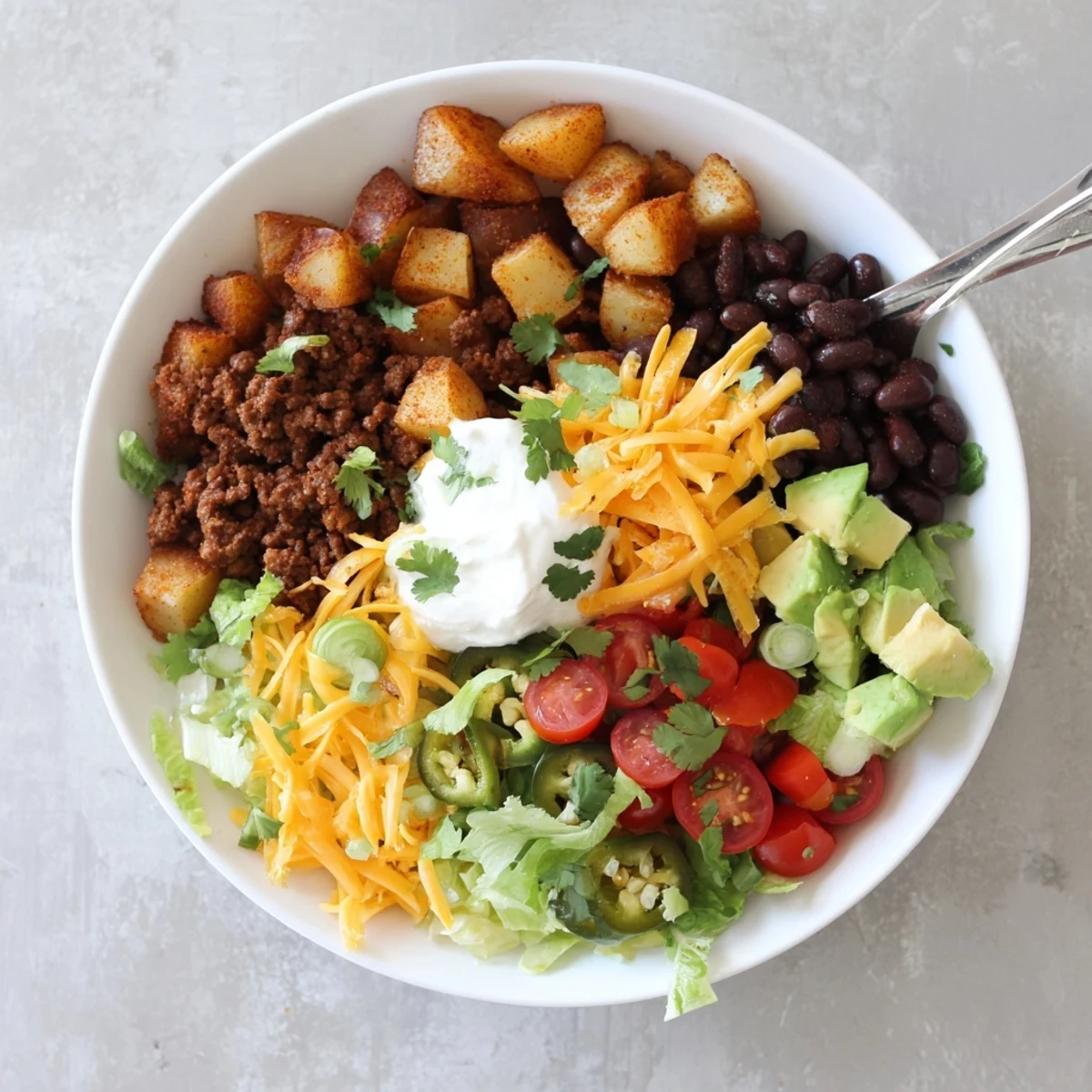 Golden roasted potato taco bowl topped with seasoned beef and colorful fresh toppings