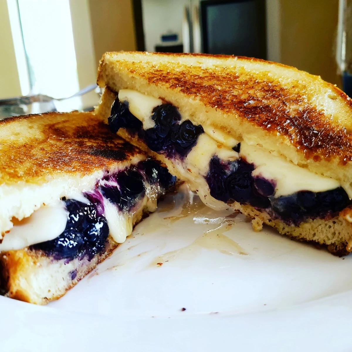 Halved blueberry grilled cheese revealing warm blueberry filling between golden brown cheesy bread layers