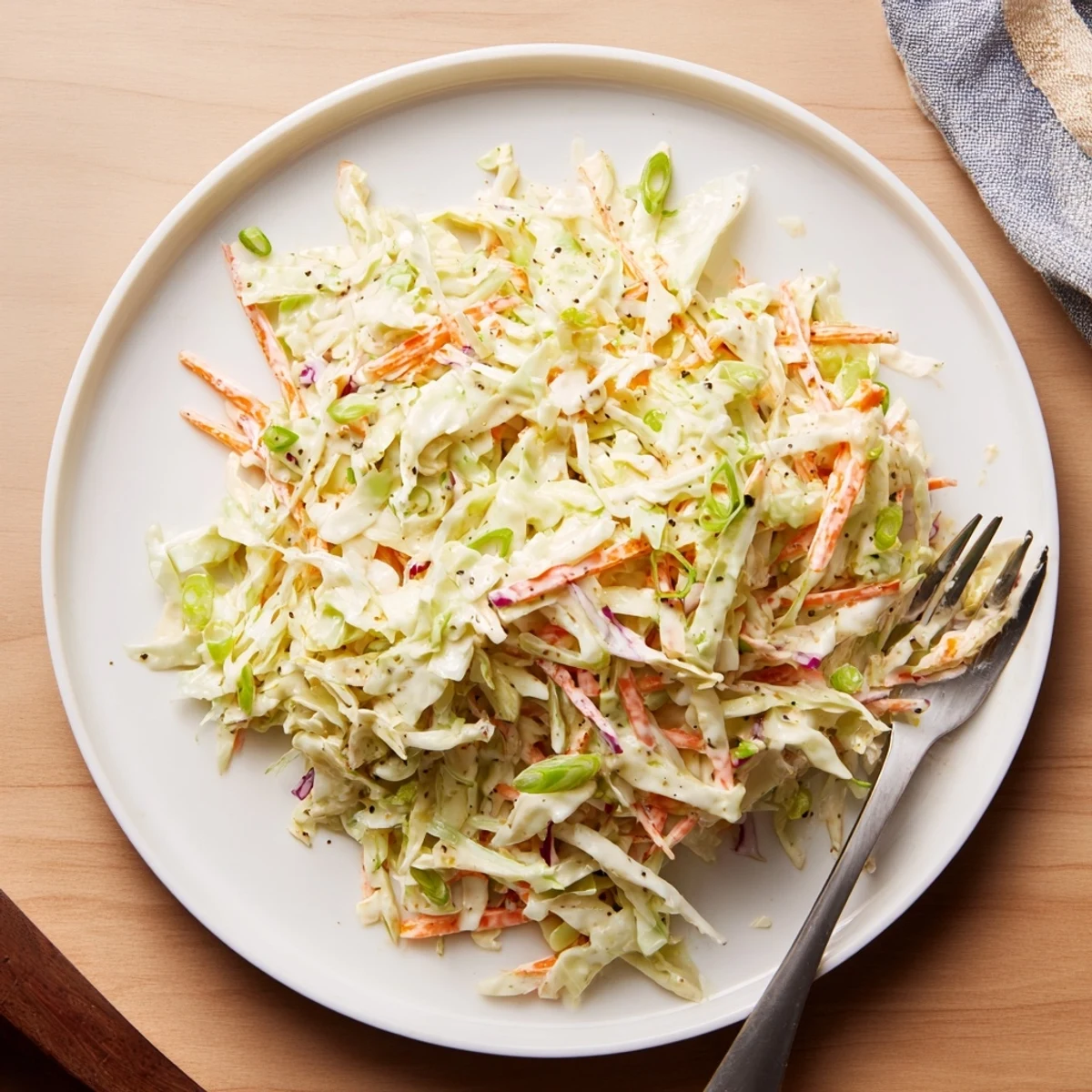 Golden easy creamy coleslaw served alongside grilled barbecue ribs on a rustic wooden platter