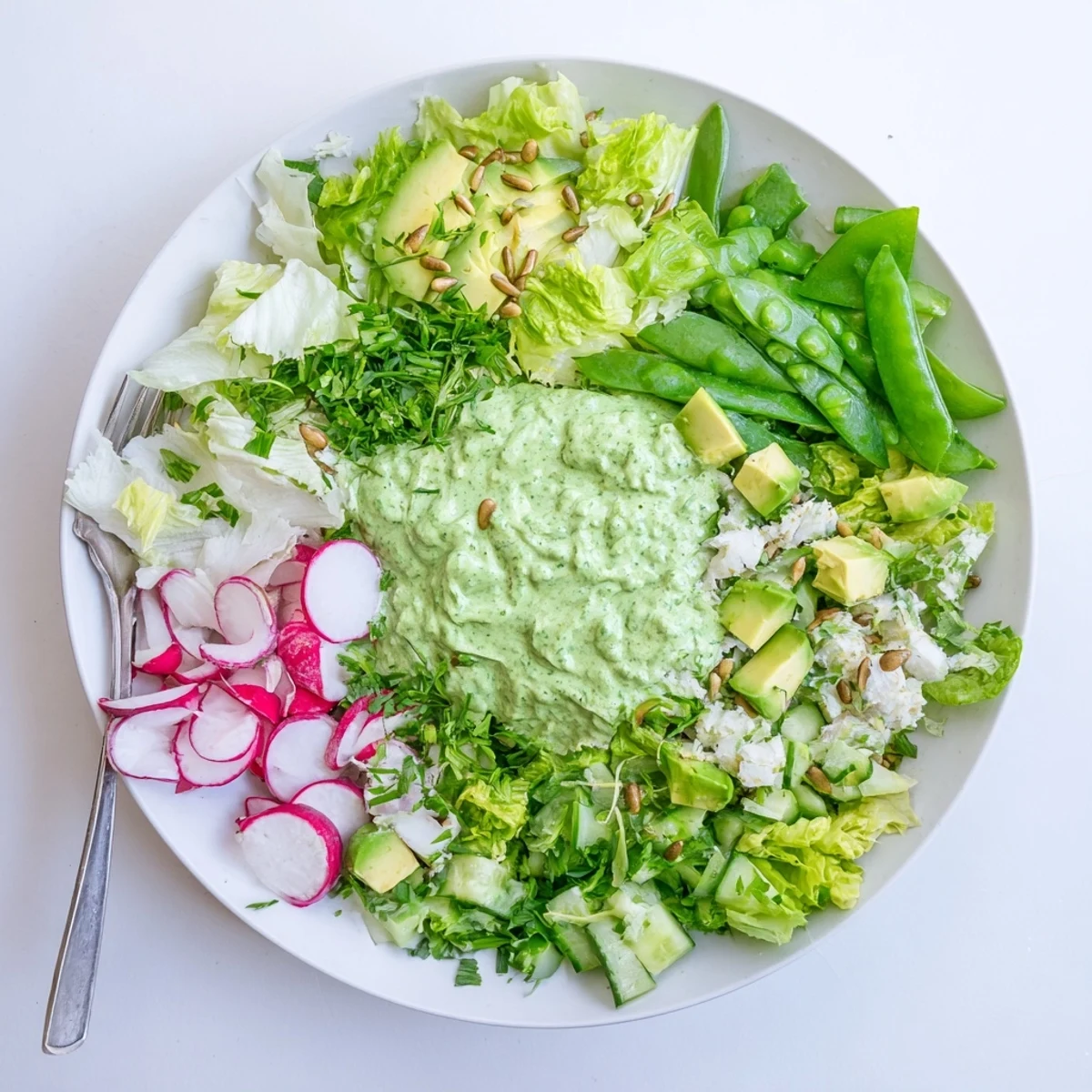 Light and refreshing green goddess salad plated with mixed greens, radishes, and bright green goddess dressing