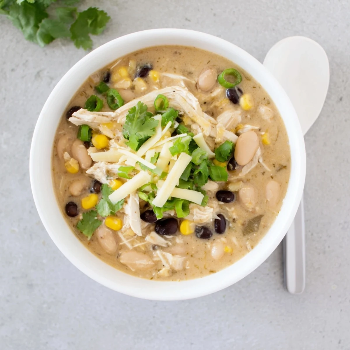 Creamy white chicken chili bowl topped with cheese, cilantro and lime wedges
