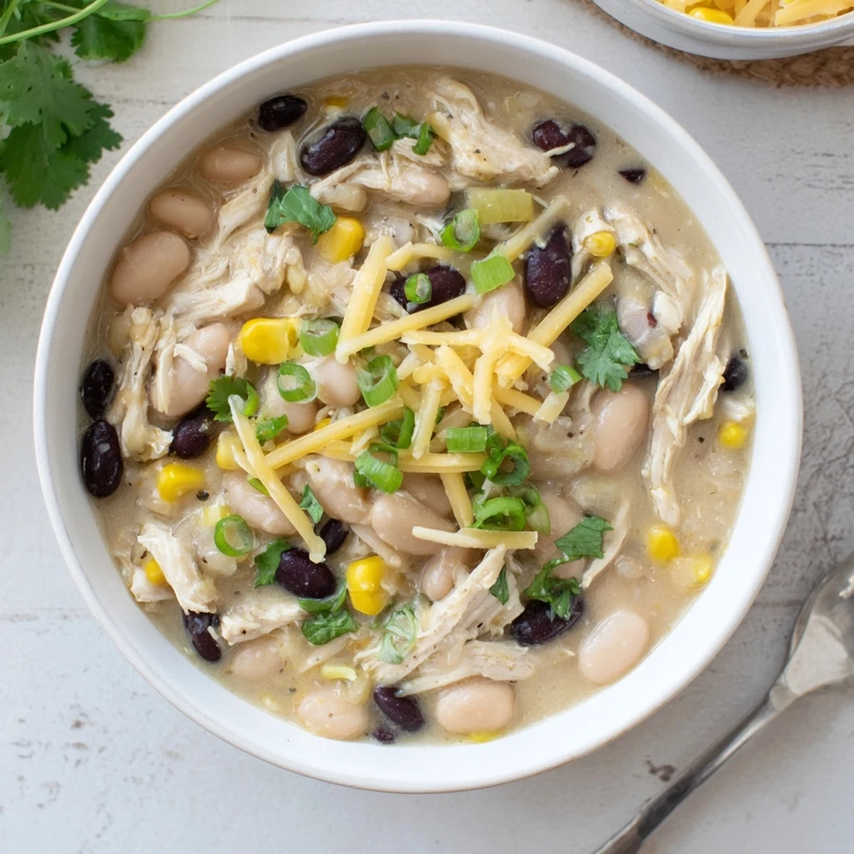 Spoonful of rich white chicken chili showing tender chicken and colorful vegetables