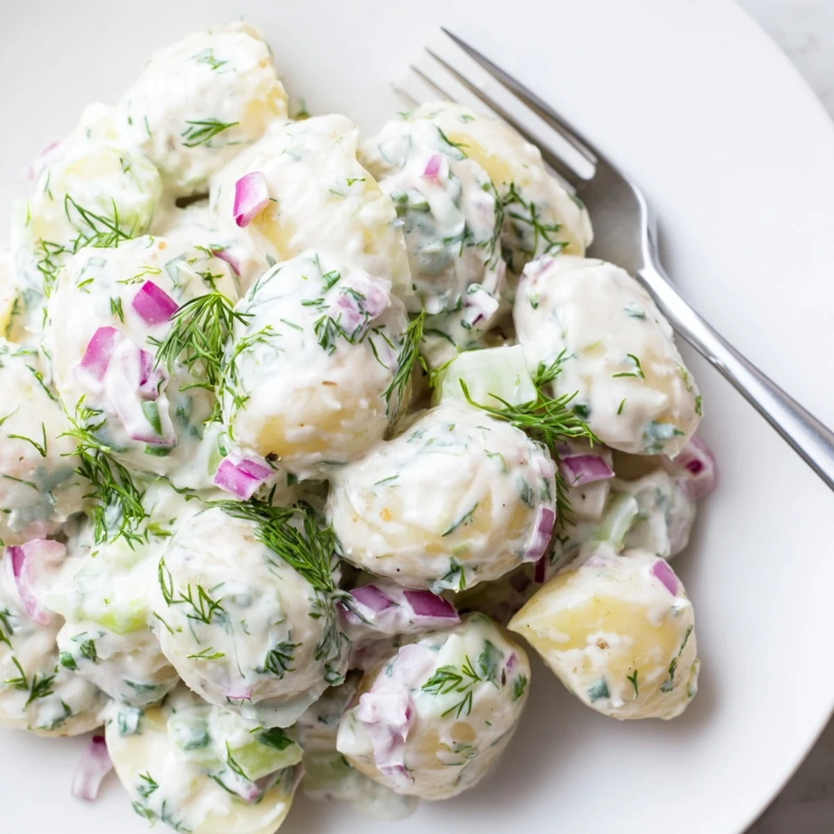Light Greek yogurt potato salad with chopped fresh parsley and dill garnish, perfect for summer gatherings