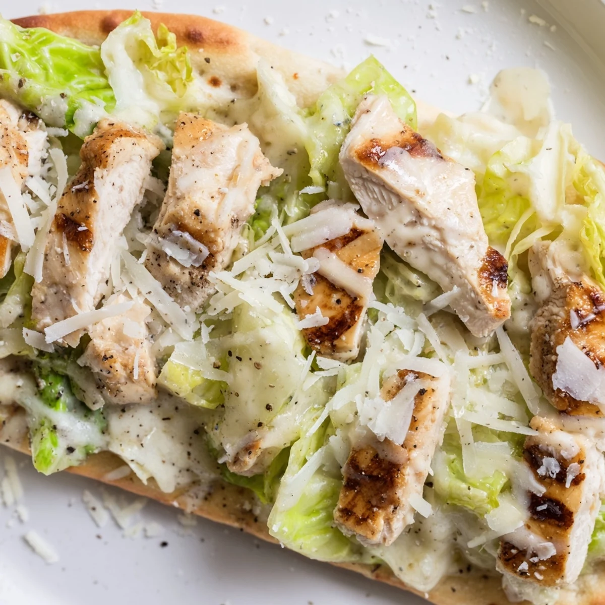 Homemade chicken Caesar flatbread loaded with seasoned chicken breast and fresh lettuce toppings
