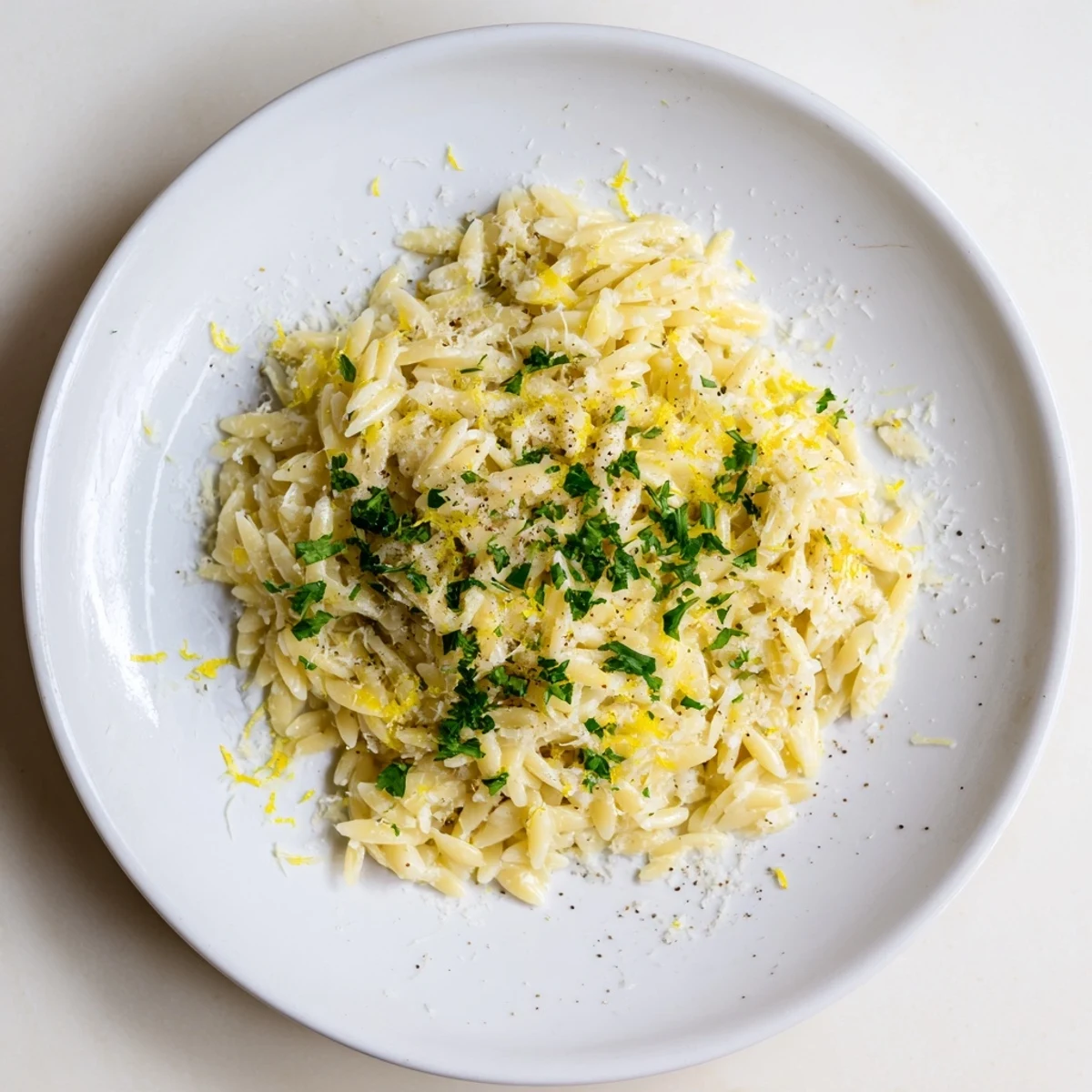 Bright lemon orzo dish garnished with parsley and grated cheese on a rustic table