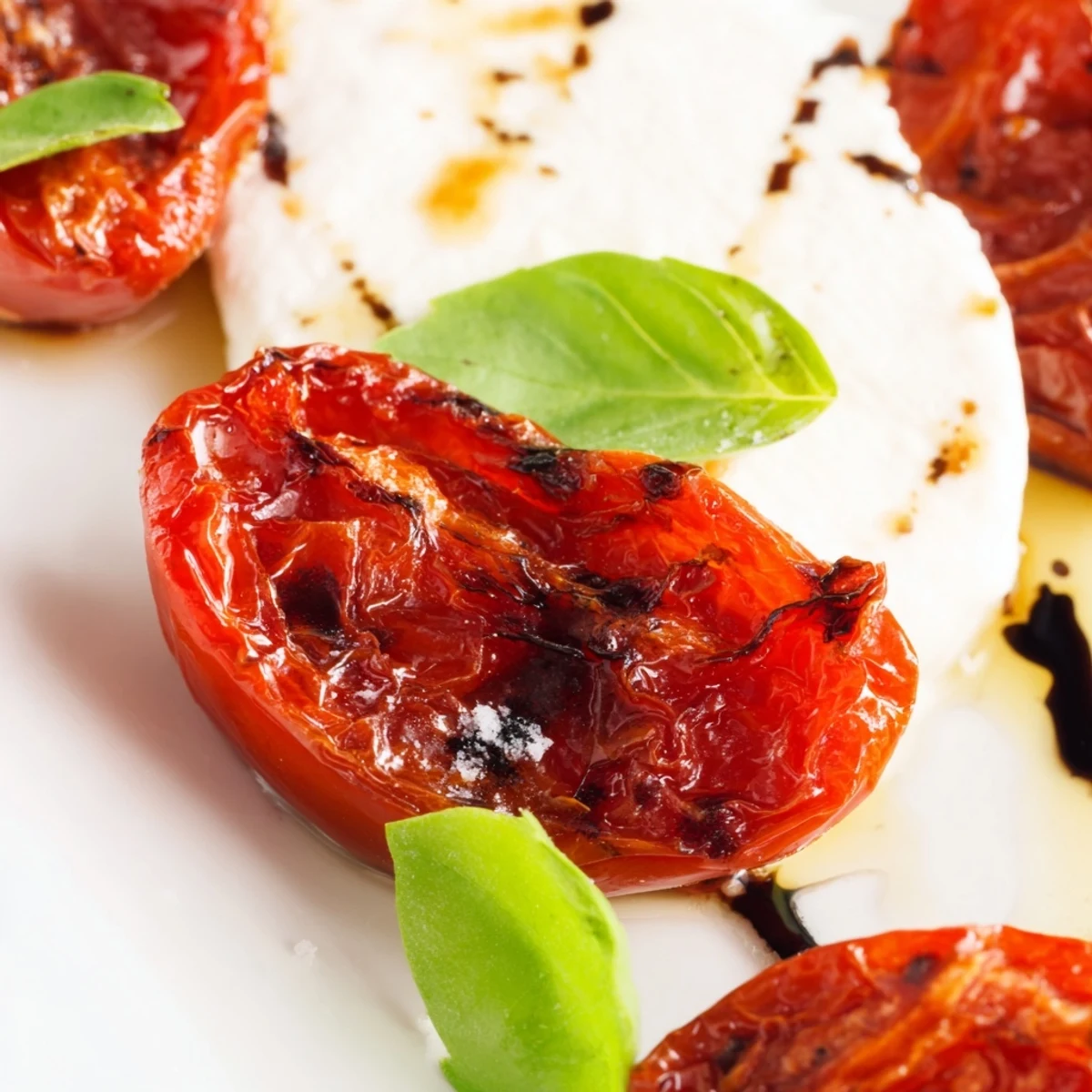 Italian-style roasted tomato Caprese salad arranged with creamy cheese and dark balsamic swirls