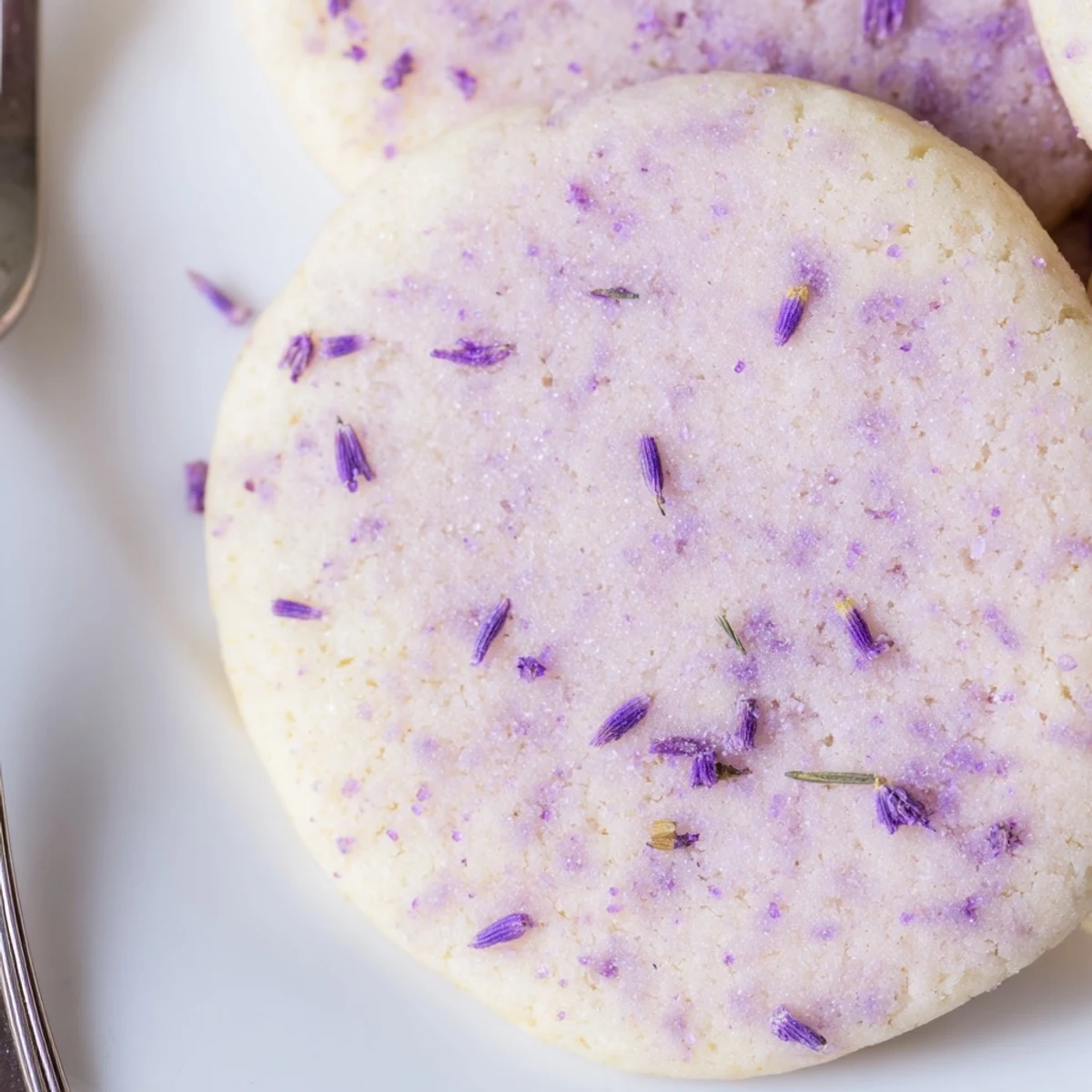 Buttery lilac sugar cookies arranged on a rustic white serving plate