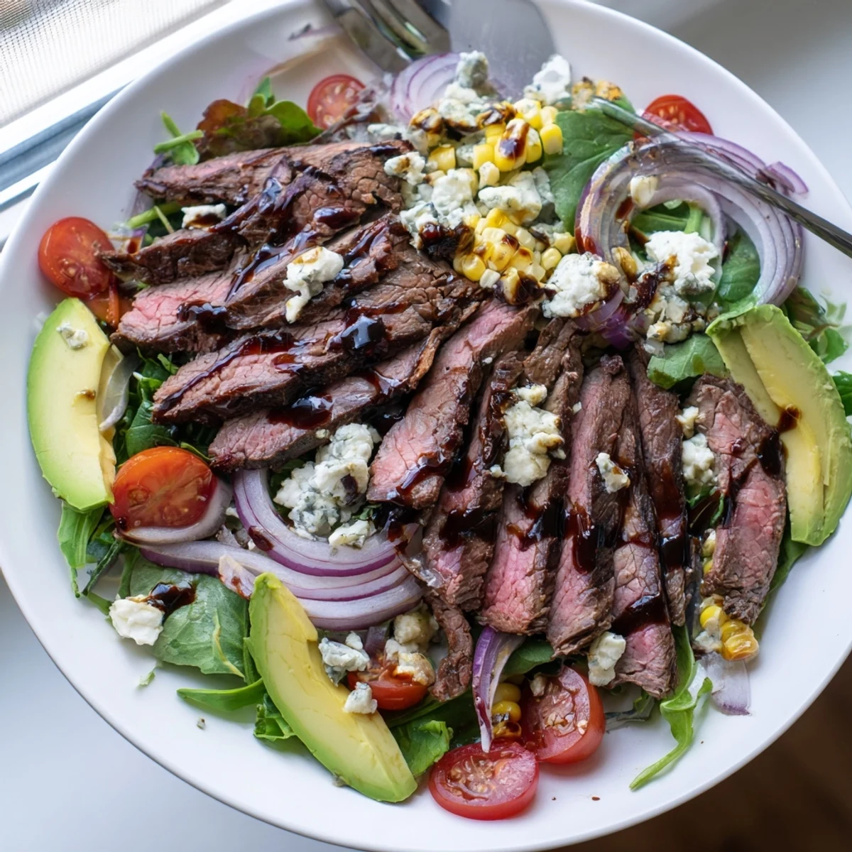 Crisp greens topped with tender grilled steak, creamy Gorgonzola crumbles, and sweet golden grilled corn in this balsamic steak Gorgonzola salad.